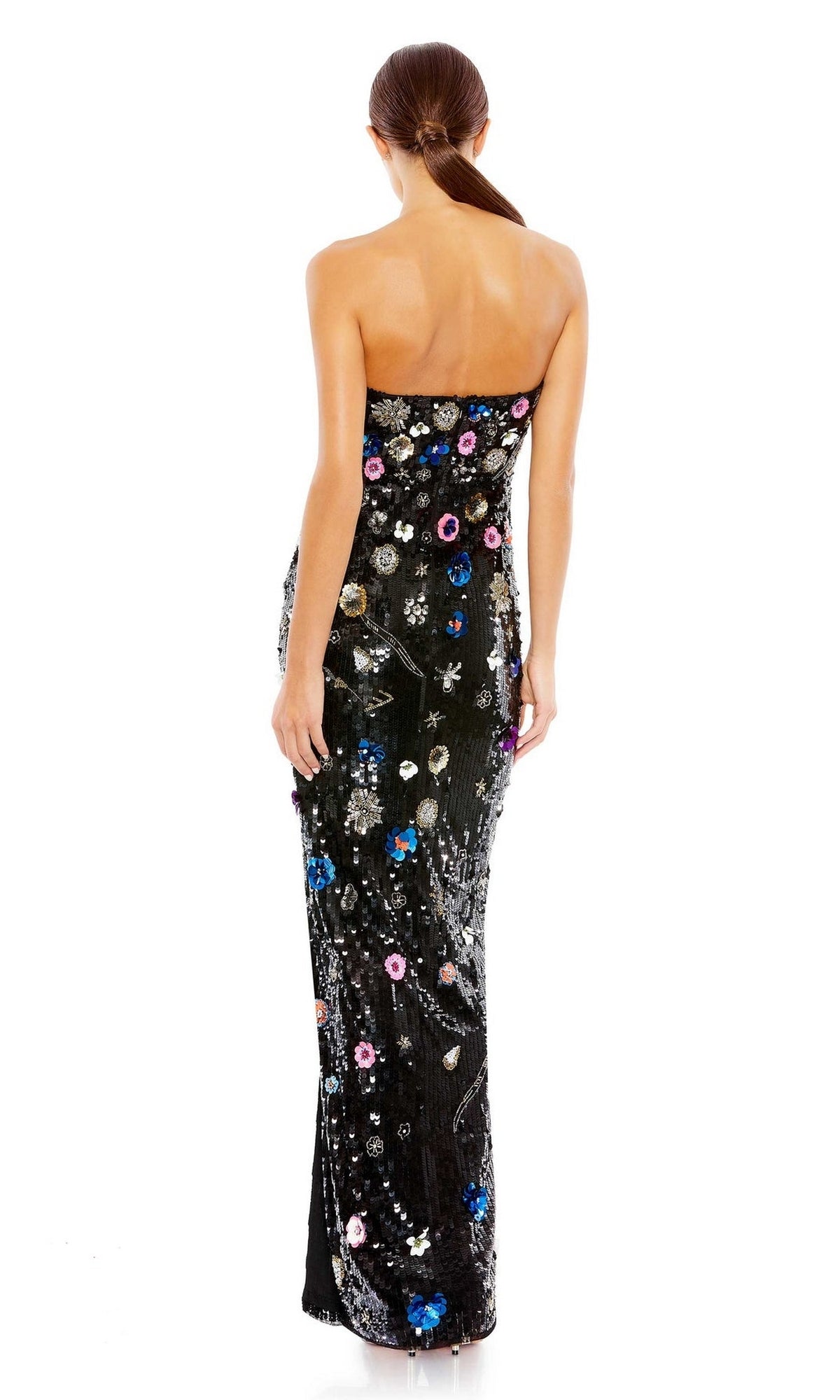 A woman faces away in the Long Formal Dress 93695 by Mac Duggal—a strapless, floor-length black gown featuring colorful floral patterns on a white background.